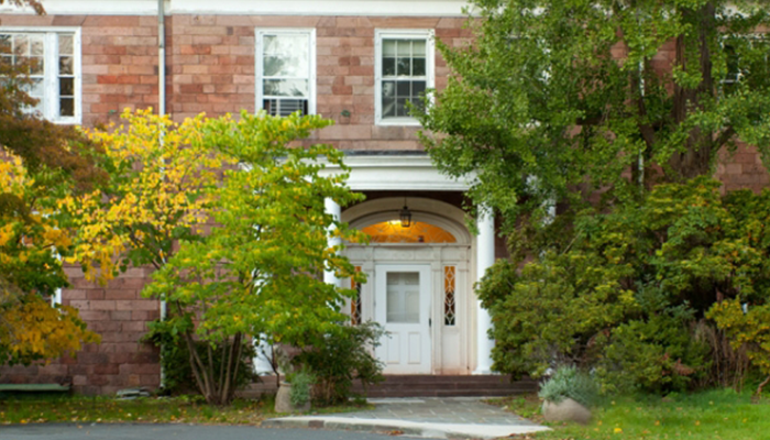 A view of the front of Lamont Hall among the bushes. 