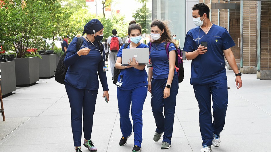 Medical staff at Columbia walk down the sidewalk with facemasks.