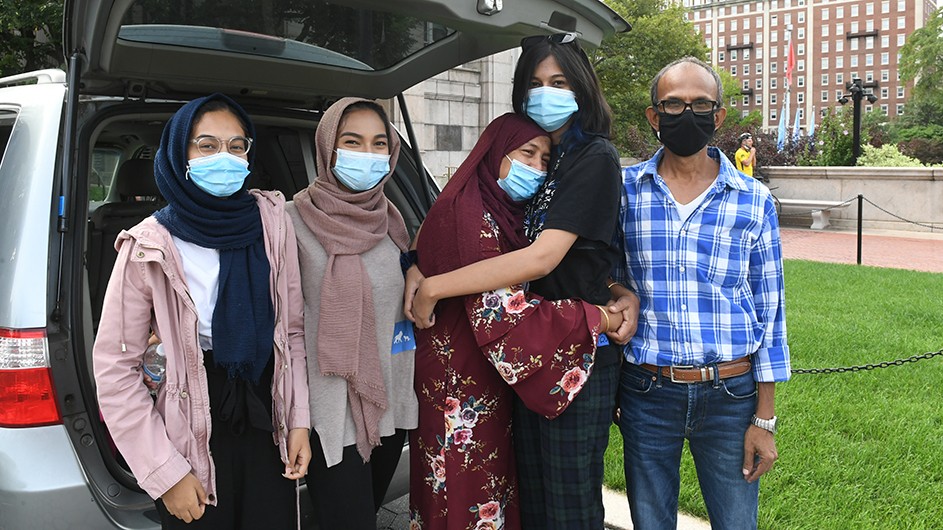 A family in masks poses by a student moving  into Columbia's dorms. 