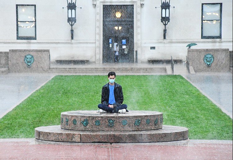 A student meditates on the sundial in front of Butler Library. 