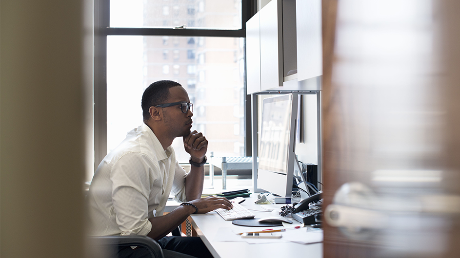 An office worker stares at a computer alone.