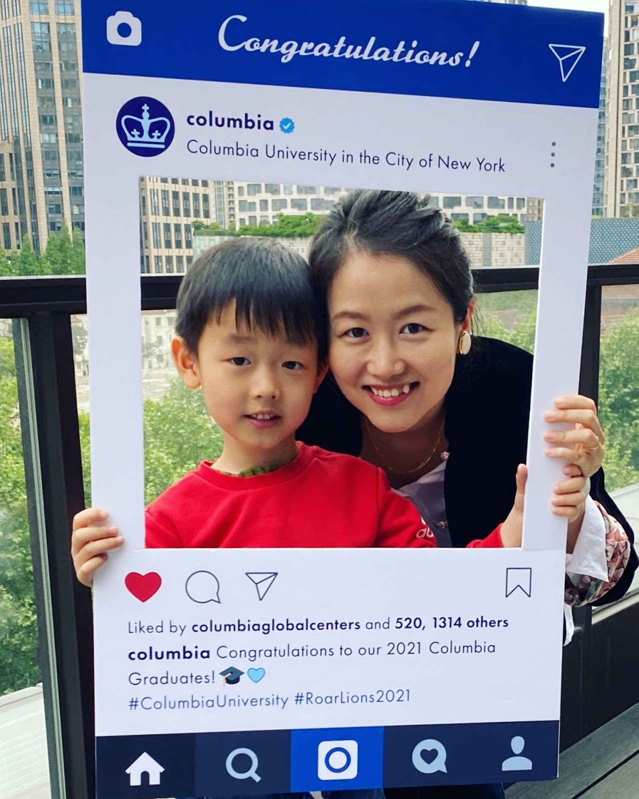 A Columbia grad poses with a young boy in an instagram cutout. 