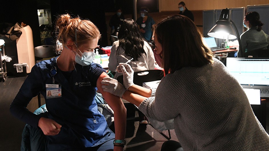 Photo by Eileen Barroso for Columbia University Irving Medical Center A woman receives a shot in the arm with a COVID-19 vaccine.