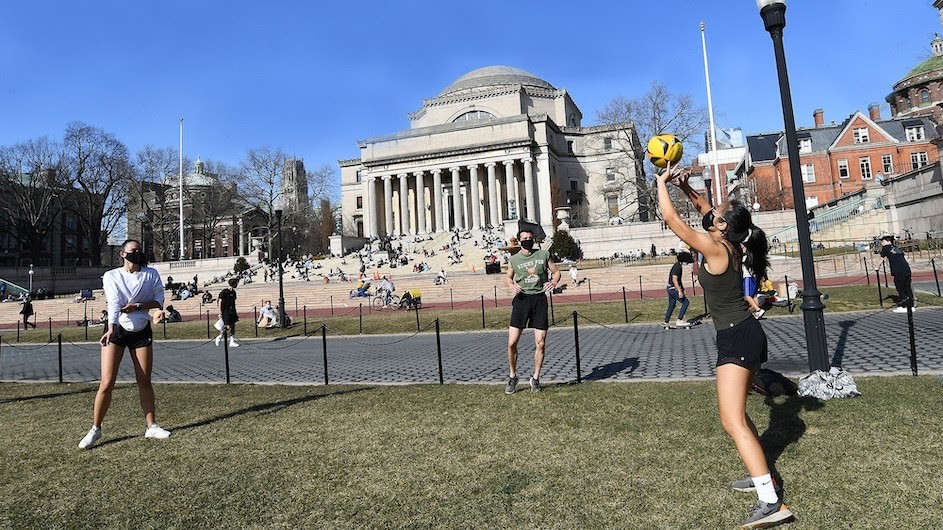 Two Columbia students play volleyball in front of Low Library
