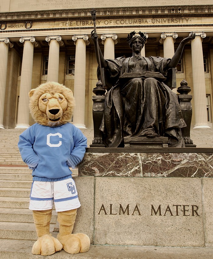 Photo by Eileen Barroso Roar-EE in a sweater poses next to Alma Mater