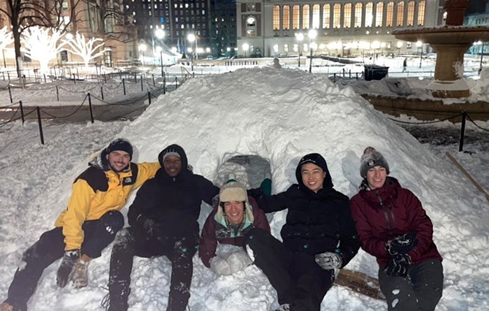 Students sit on a constructed snow igloo in front of Butler Library. 
