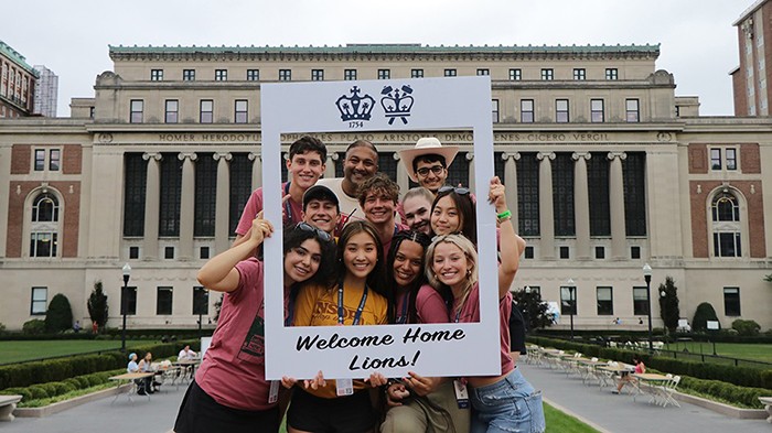 Students pose with a cardboard cutout of a polaroid in front of Butler Library