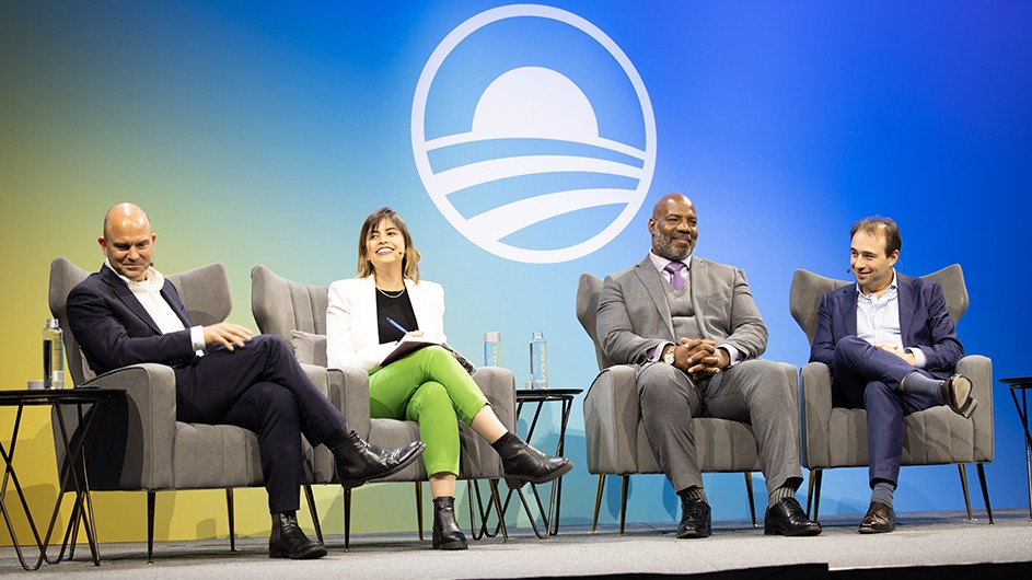 Four people sitting on chairs on a stage, having a discussion. 