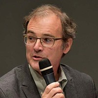 A man with short hair and glasses, in a suit