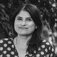 A woman with long dark hair in a top with dots, in black and white.  