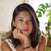 A woman with medium-length dark hair, in a white top.