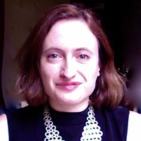 Eliza Zingesser A woman with medium length brown hair in a black top.