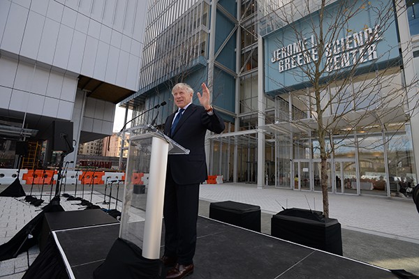 Lee Bollinger standing at a podium in front of the Jerome L. Greene Science Center. 