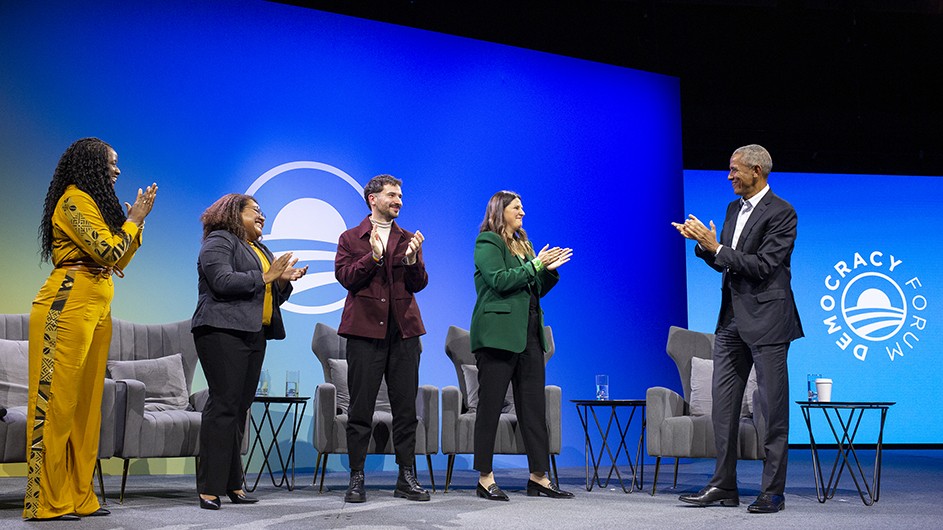 Doussouba Konaté, Mali, Africa Leader 2022; Landisang Kotaro, Palau, Asia-Pacific Leader 2022; Nick Antipov, Belarus, Europe Leader 2020; Natalia Herbst, Argentina, Columbia Scholar 2019-2020; and former U.S. President Barack Obama. Photo: The Obama Foundation. Five people, including former President Obama, standing on a stage, clapping.