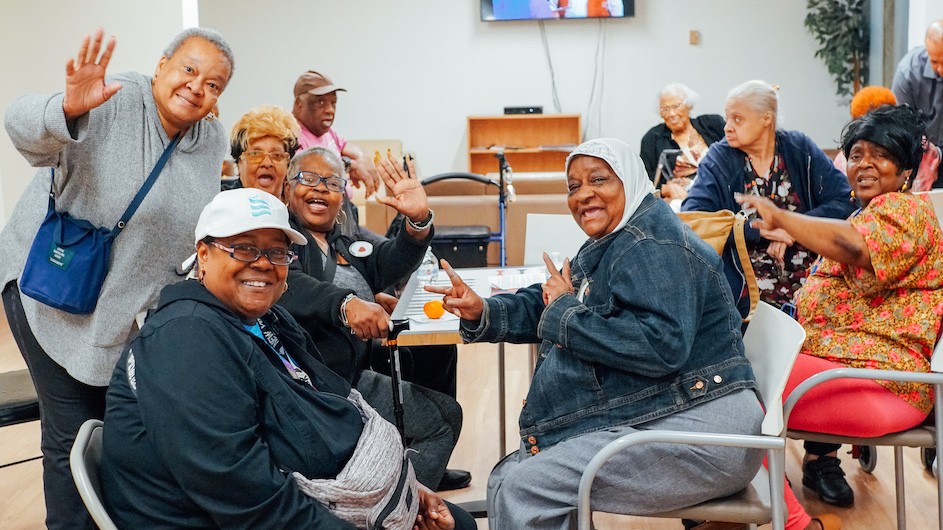 Several women seated and standing waving at the camera