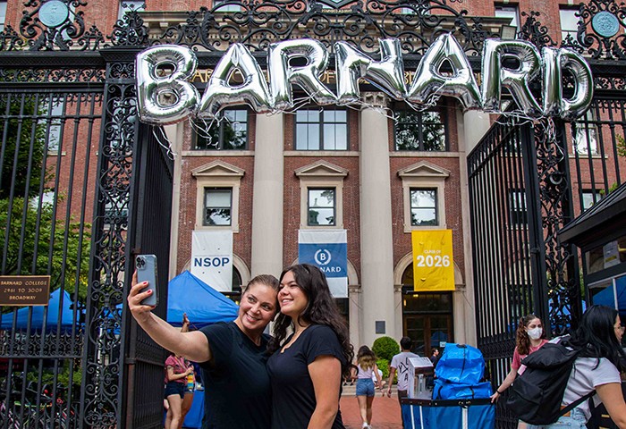 Students take a photo with Barnard balloons under the gates. 