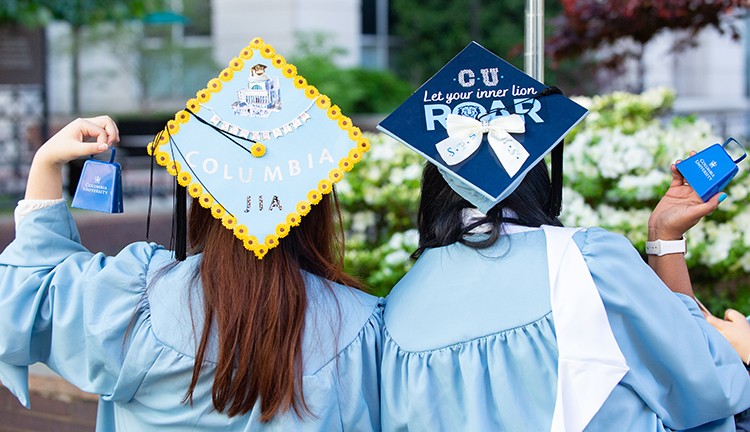 Two Columbia grads show off their decorated mortar boards on Commencement day. 