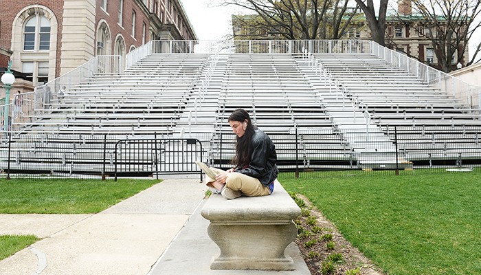A student sits in front of constructed bleachers on Low Plaza.