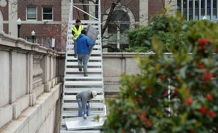 Two workers load up the bleachers on Low Plaza.
