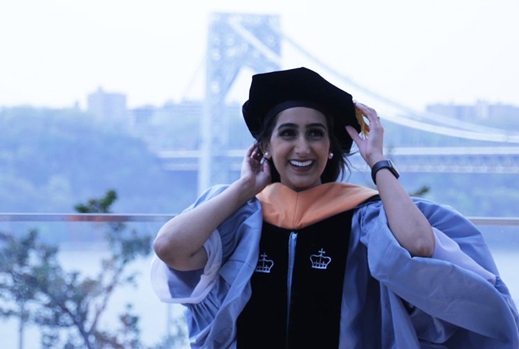 Manpreet Nijjar (NUR'21). Photo by Janine Inez. Manpreet Nijjar (NUR'21) adjusts her velvet tam on the CUIMC campus with the George Washington Bridge in the background.