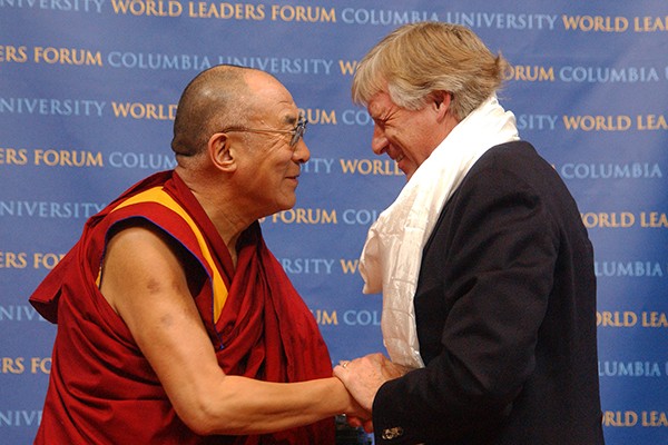 Two men, Lee Bollinger and the Dalai Lama, greet each other. 