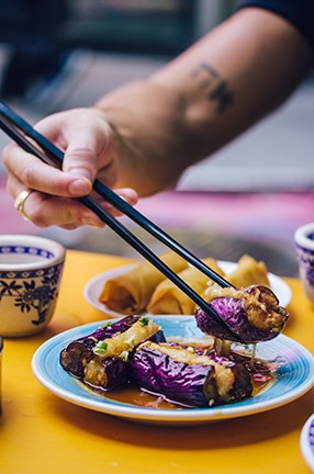 Picking up spring rolls off a plate with chopsticks.