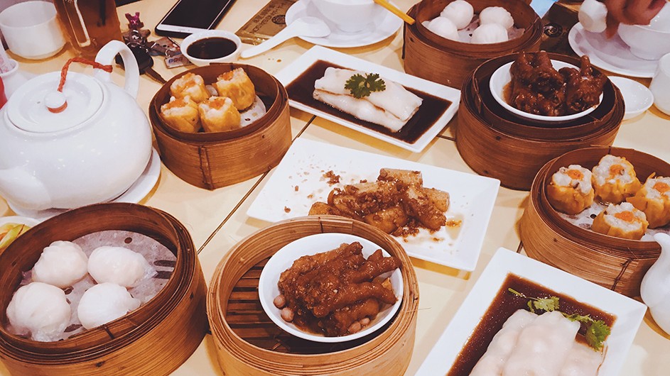 Dumplings and other Chinese food in bamboo steamer baskets on a table.