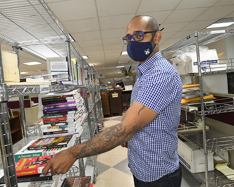 Freddy Claudio at work in Columbia's Butler Library during the pandemic. Photo by Eileen Barroso. Freddy Claudio at work shelving books in a Columbia face mask.