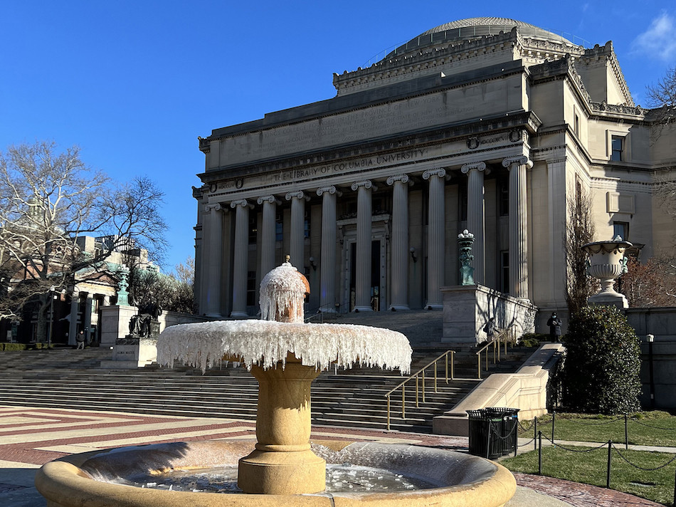 Ice-coated garden fountain beginning to thaw on a sunny early-spring day