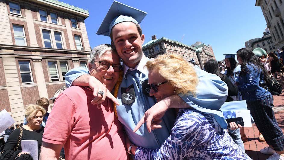 Patrick Eby (CC'19) with his parents at the 2019 commencement ceremony. Photo credit: Eileen Barroso Two parents hugging their son at Columbia's graduation