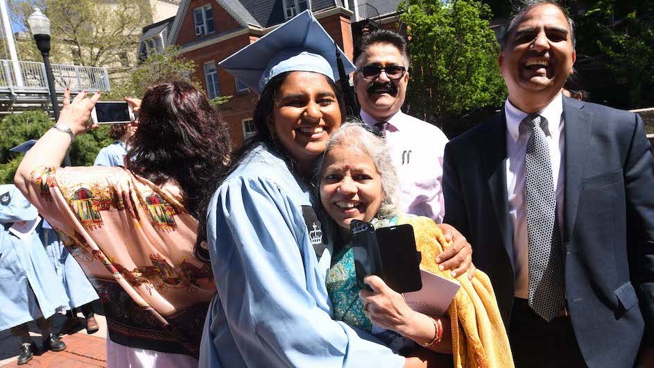Columbia University graduate in cap and gown with her relatives