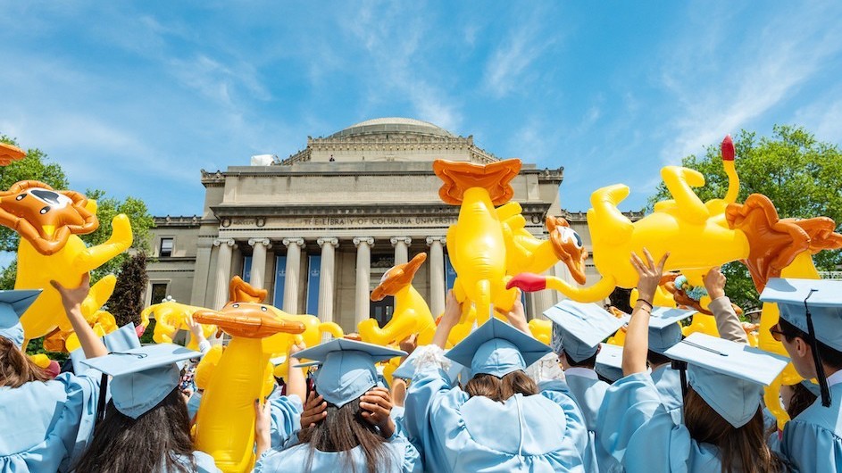 Columbia graduates holding up inflatable lions at commencement, May 2022