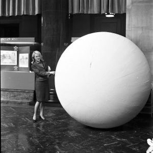 Low Library “moon” removal, January 25, 1965. Scan 4964. Office of Public Affairs photograph collection, University Archives. Low moon ball with woman for scale