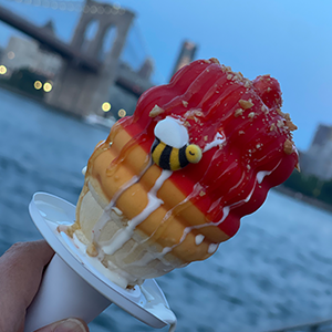 先生蘸冰淇淋蛋筒与布鲁克林大桥在背景中。