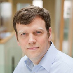 Headshot of Matthew Palmer, a person with short dark hair, in a light blue shirt. 