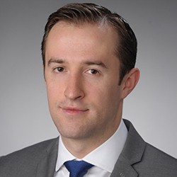 Headshot of Yevgeniy Yesilevskiy, a person with short dark hair in a dark suit. 