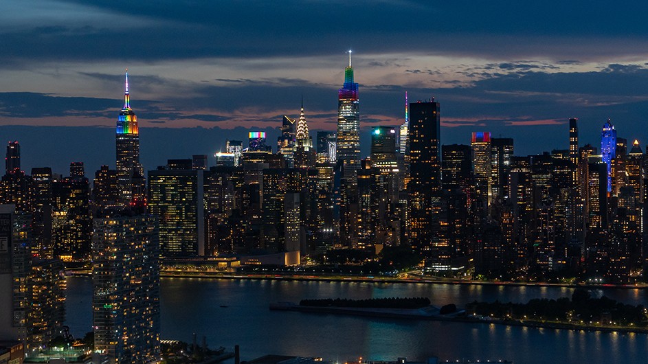 The Manhattan skyline at night with skyscrapers lit up for Pride.