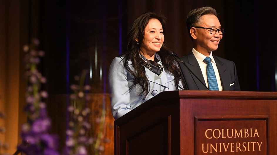 Shirley and Walter Wang speaking at a Columbia celebration honoring their recent gifts to the University. Photo: Eileen Barroso Shirley and Walter Wang, in a light blue suit and a dark suit, standing at a podium with the words "Columbia University in the City of New York" on it.