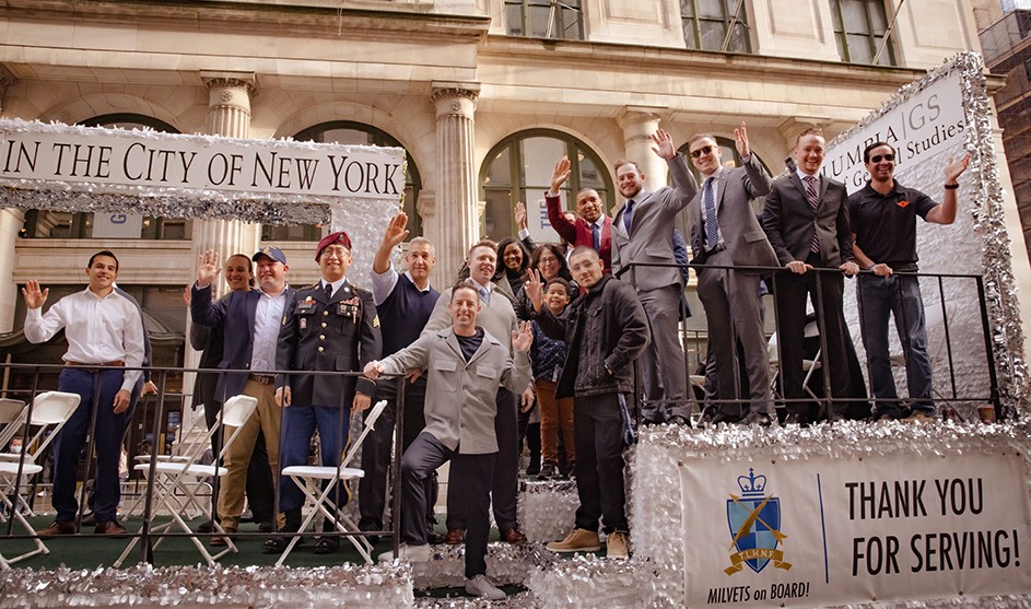 Columbia General Studies military veteran students waving on a parade float with Dean Lisa Rosen-Metsch at the 2021 Veterans Day Parade in New York City.