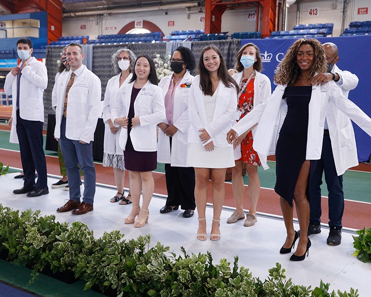 Part of orientation activities include "White Coat" ceremonies, ushering in new classes of nursing, dental, medical, and physical therapy students. Photo by Michael DiVito. Medical students pose in white coats.