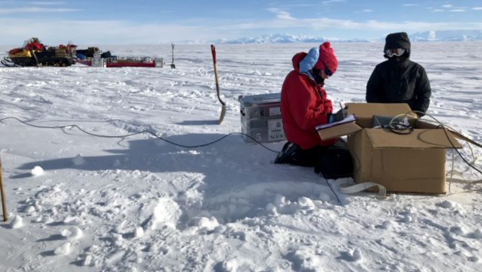Geophysicist Chloe Gustafson and mountaineer Meghan Seifert install an instrument that measures electromagnetic fields on the Whillans Ice Stream in West Antarctica. (Image: Kerry Key, Lamont-Doherty Earth Observatory, Columbia University)