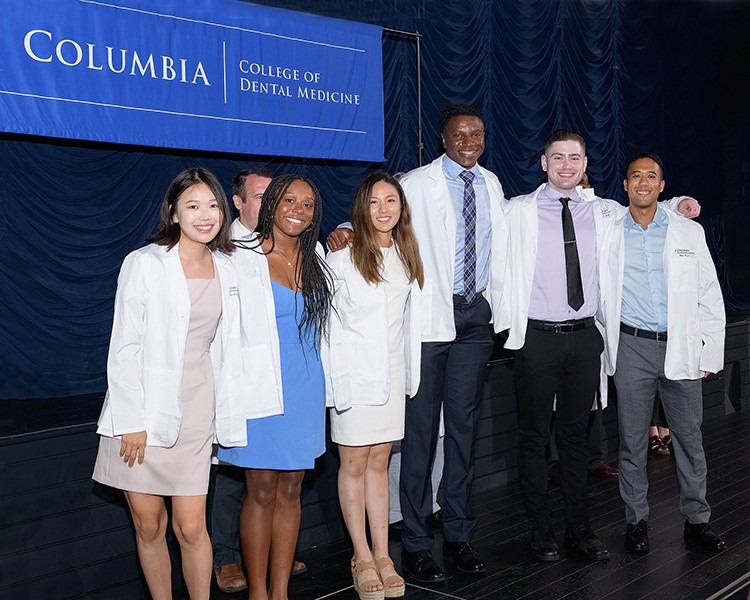Part of orientation activities include "White Coat" ceremonies, ushering in new classes of nursing, dental, medical, and physical therapy students. Photo by Charles Manley. Students in the College of Dental Medicine pose in their white coats.