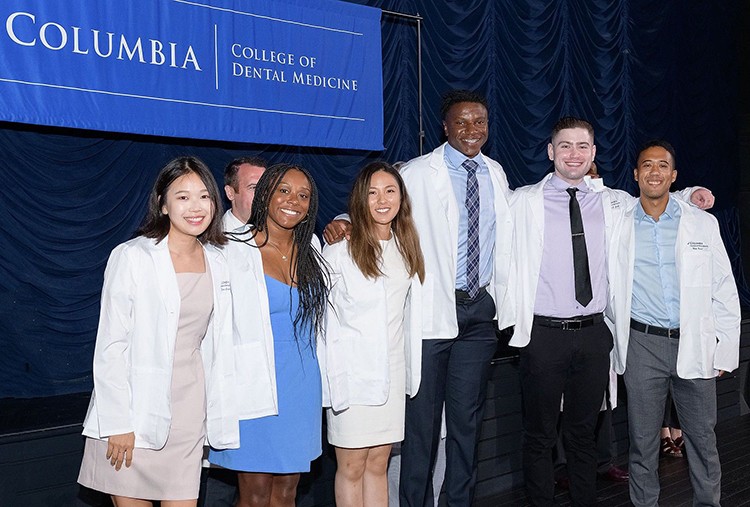 Part of orientation activities include "White Coat" ceremonies, ushering in new classes of nursing, dental, medical, and physical therapy students. Photo by Charles Manley. Students in the College of Dental Medicine pose in their white coats.