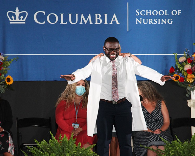 A Nursing School student has a white coat placed on him during the white coat ceremony.