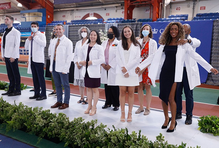Part of orientation activities include "White Coat" ceremonies, ushering in new classes of nursing, dental, medical, and physical therapy students. Photo by Michael DiVito. Medical students pose in white coats.