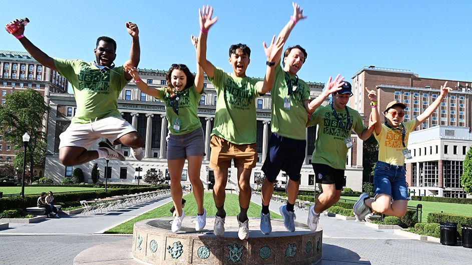 Six students in NSOP shirts jump off of Columbia's sundial in happiness during welcome.