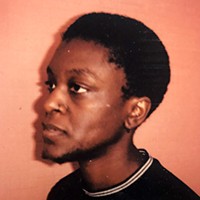 A person with short dark in profile, in a black top.