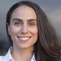 A woman with long dark hair in a white top. 