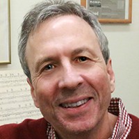 A man with short white hair in a red top. 