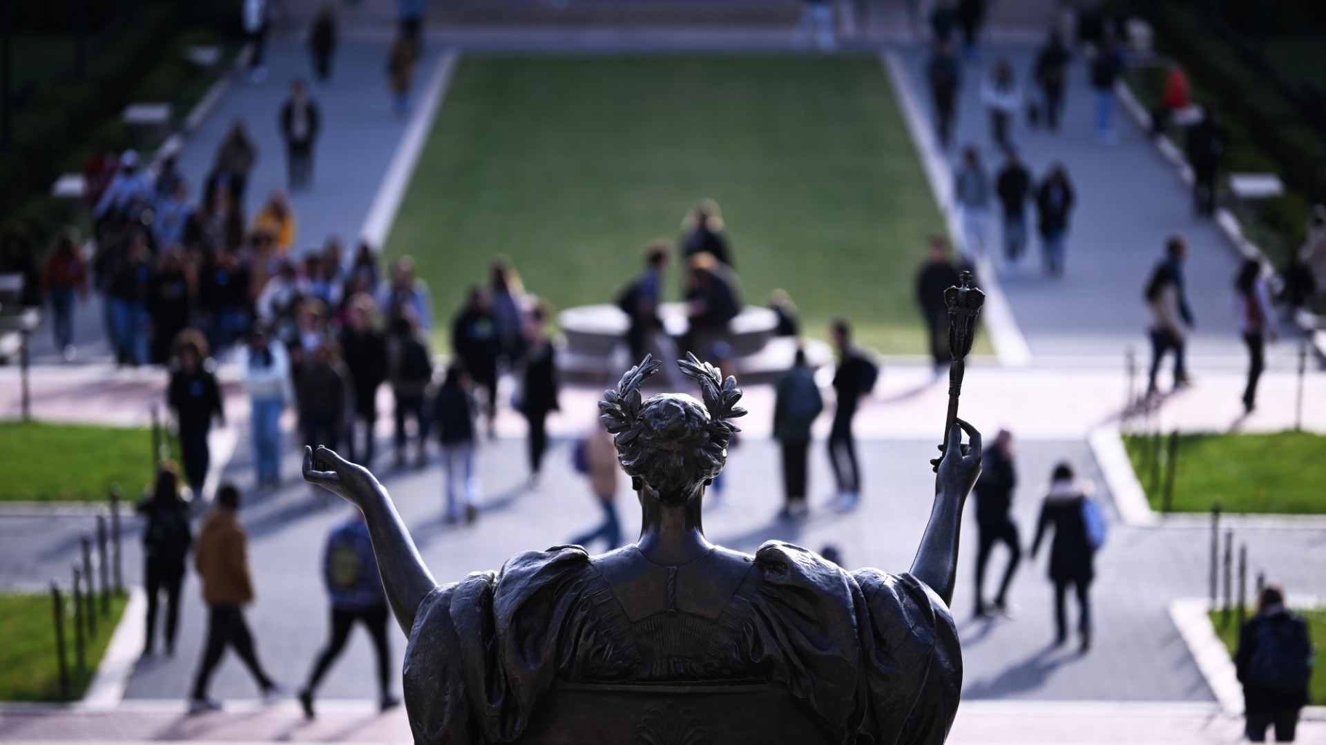 People walking around on Columbia's campus, against the backdrop of the statue of Alma Mater